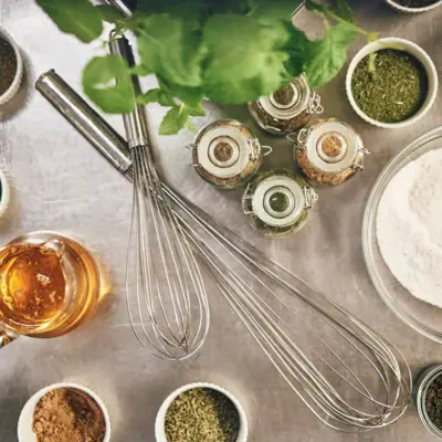 Naturprodukte Eine Gruppe von Gewürzen neben einer Schüssel mit Mehl und einem Schneebesen.