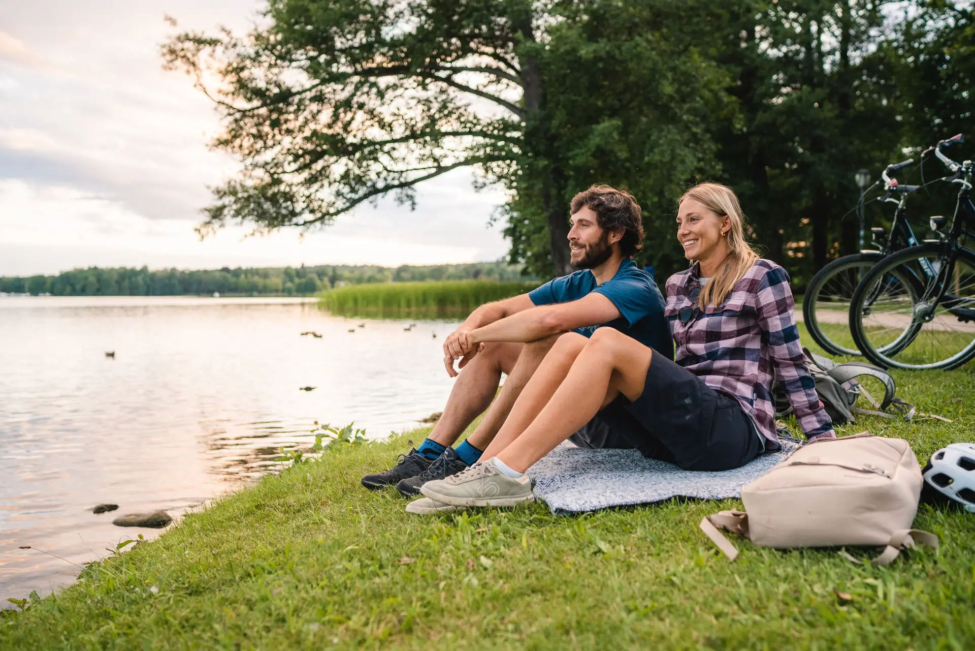 Ein Mann und eine Frau sitzen auf einer Decke am See.
