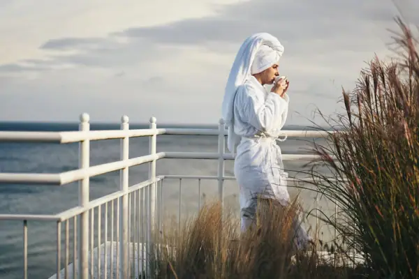 SPA Terrasse Eine Frau im Bademantel trinkt aus einer Tasse.