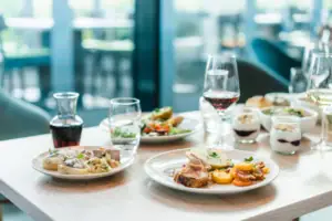 Abendessen Ein Tisch mit Tellern voller Speisen und Gläsern mit Wein.