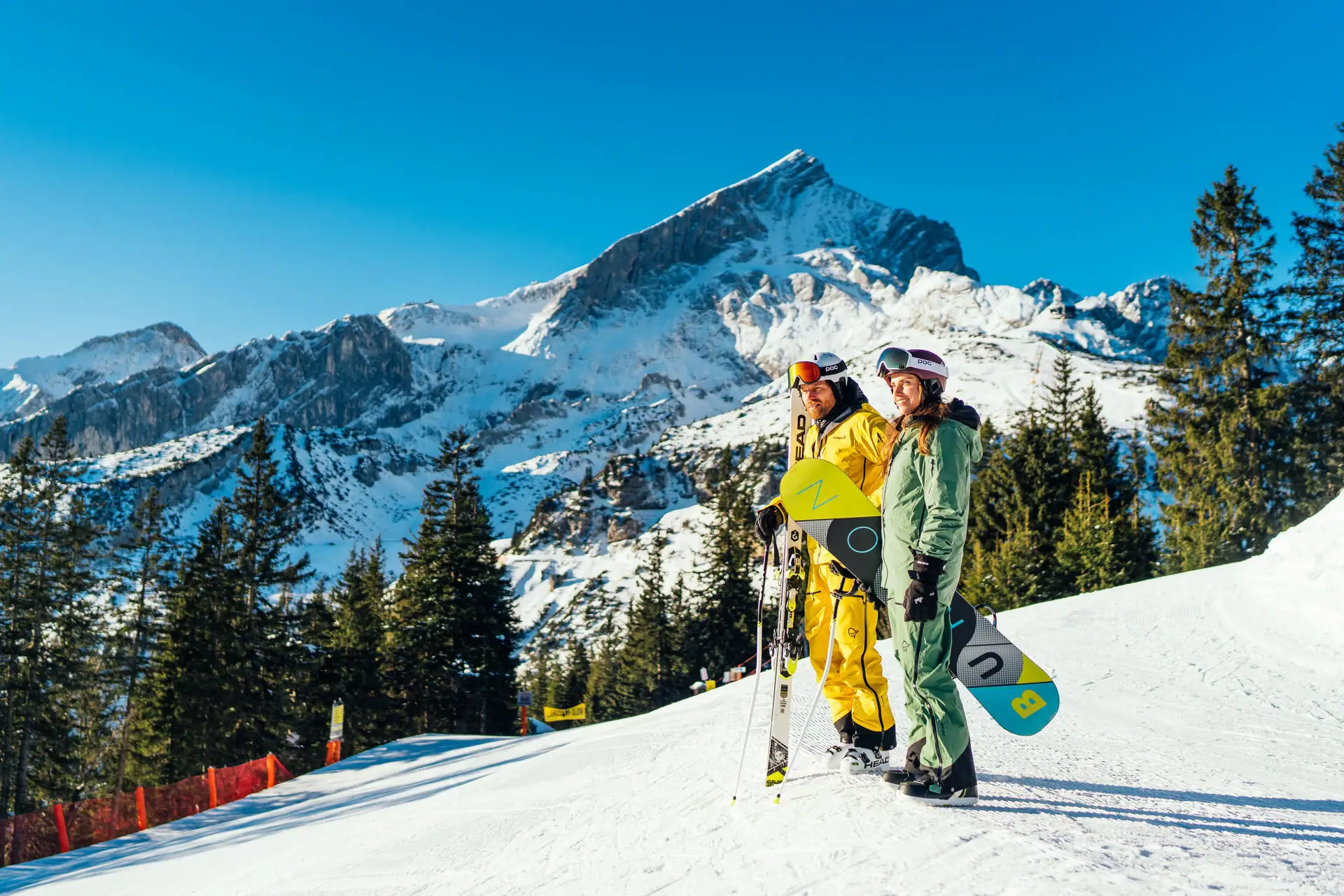 Zwei Personen in Schneekleidung auf einem verschneiten Berg.