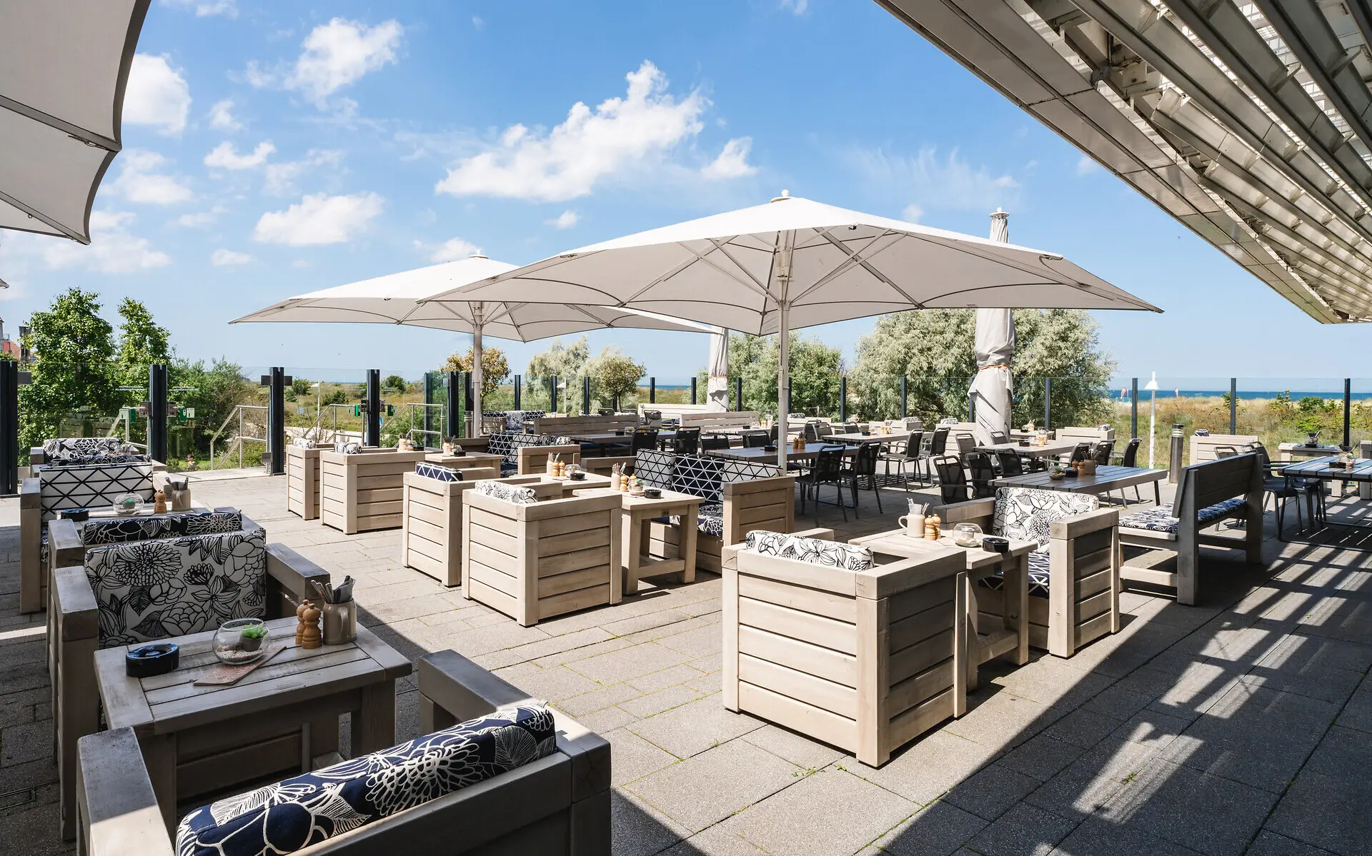 Sonnenterrasse Eine Terrasse mit Tischen und Stühlen.