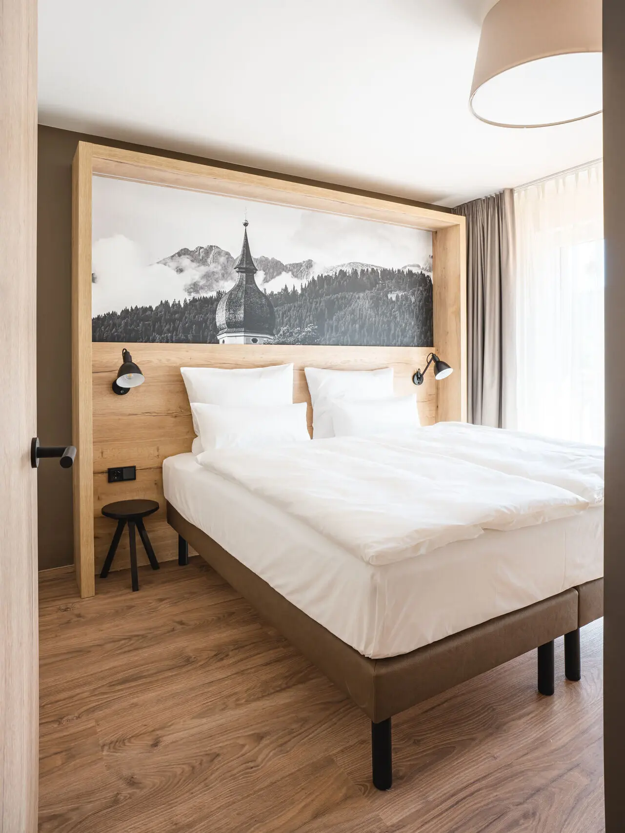 Bett mit Kissen und Bild an der Wand in einem modern gestalteten Zimmer.