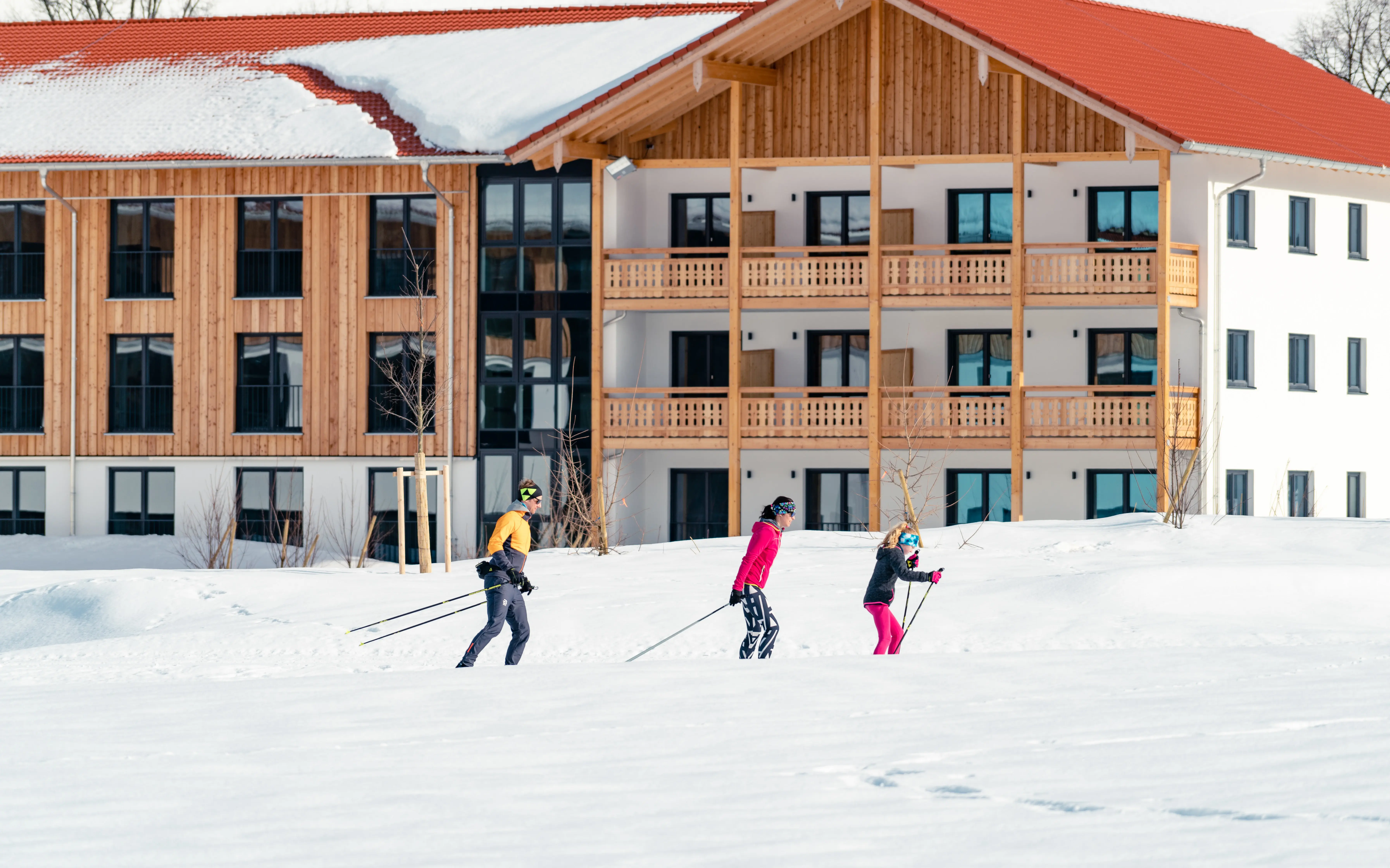 Eine Gruppe von Menschen beim Skifahren im Schnee, im Hintergrund ist das aja Ruhpolding