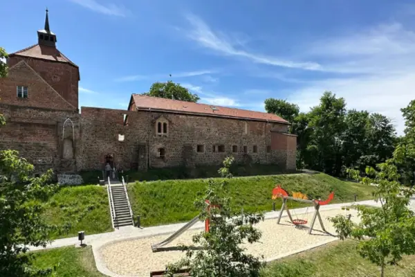 Ein Spielplatz vor einem Gebäude mit Bäumen und blauem Himmel.