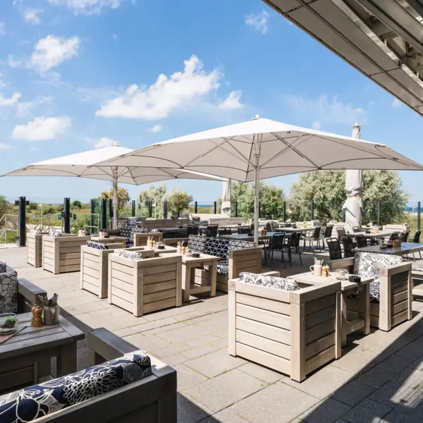 Sonnenterrasse im aja Warnemünde Eine Terrasse mit Tischen und Stühlen.