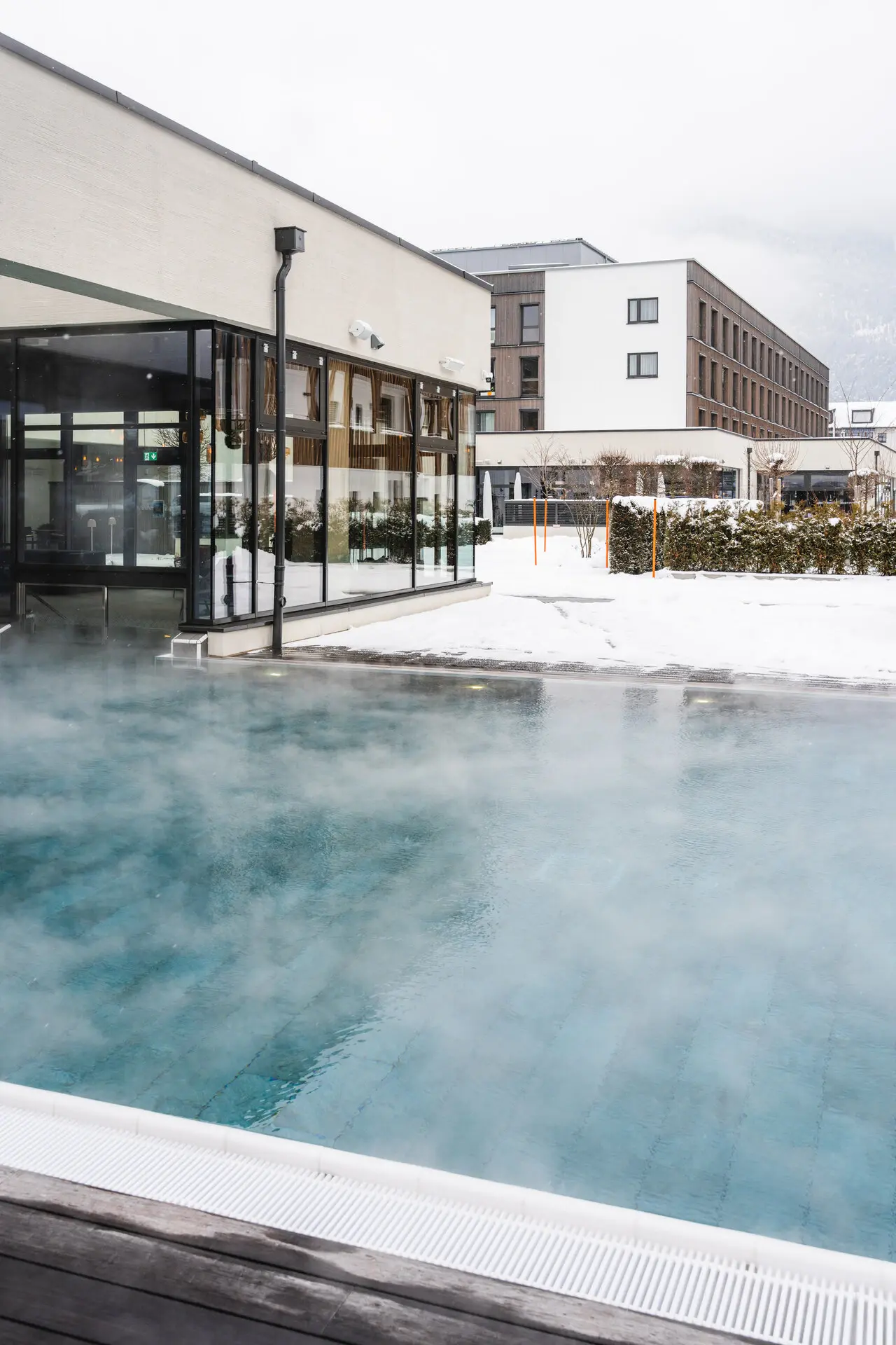 Das aja Hotel Garmisch-Partenkirchen mit einem Swimmingpool umgeben von Schnee.