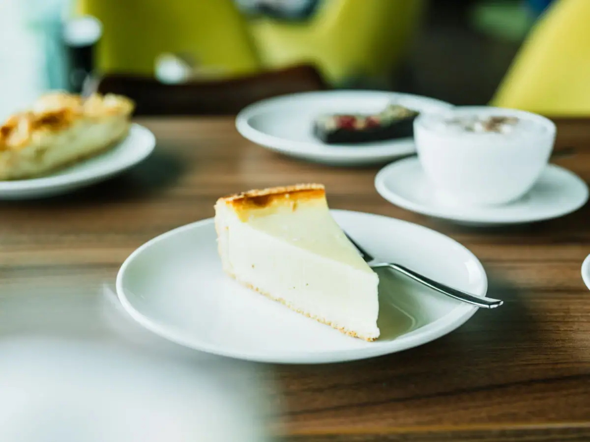Käsekuchen zur Kaffeepause im aja Ruhpolding Ein Stück Käsekuchen auf einem Teller mit einem Löffel.