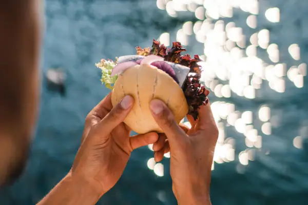 Eine Person hält ein Fischbrötchen über Wasser.