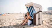 Frau sitzt in einem Strandkorb am Strand.