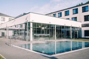Außenpool Ein Gebäude mit Pool und Fenstern im Freien.