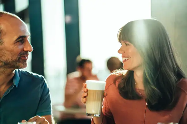 Latte Macchiato Ein Mann und eine Frau halten ein Glas Kaffee.