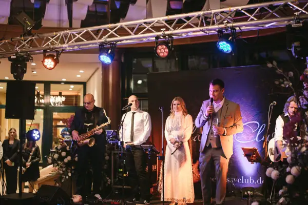 Live Musik Eine Gruppe von Menschen auf einer Bühne bei einem Konzert mit Musikinstrumenten.