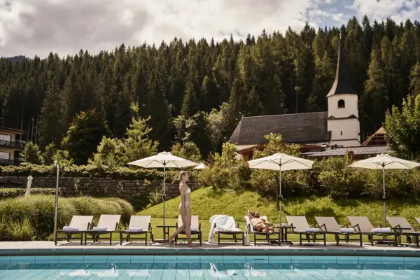 Badewelt im aja Bergresort Werfenweng Eine Frau geht an einem Pool entlang.