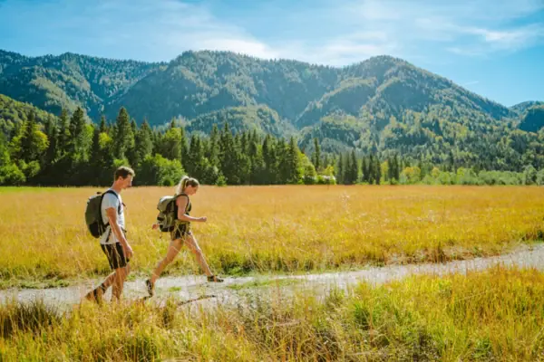 Ein Mann und eine Frau gehen in einem Feld mit Bergen im Hintergrund.