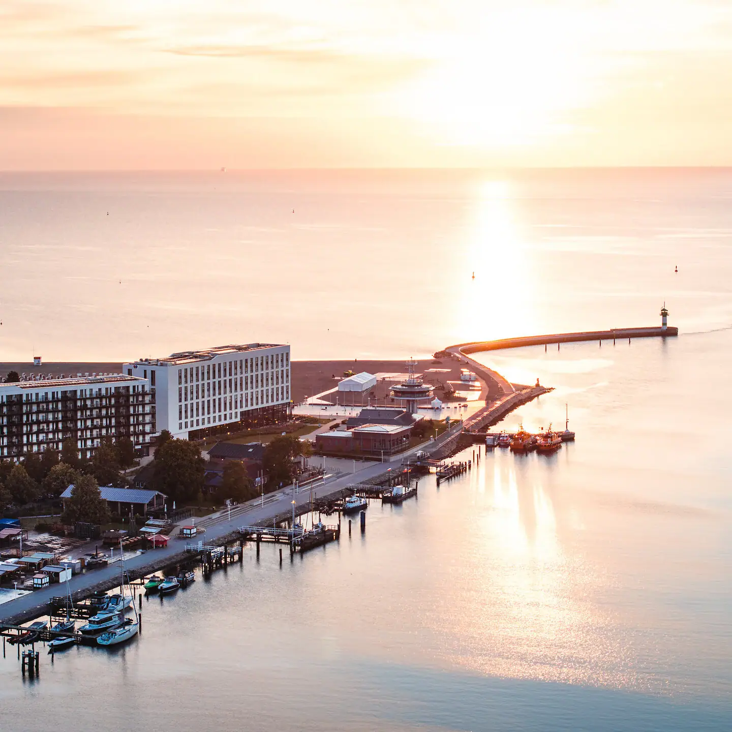 aja Travemünde Ein Gewässer mit einem Pier und Gebäuden im Hintergrund.