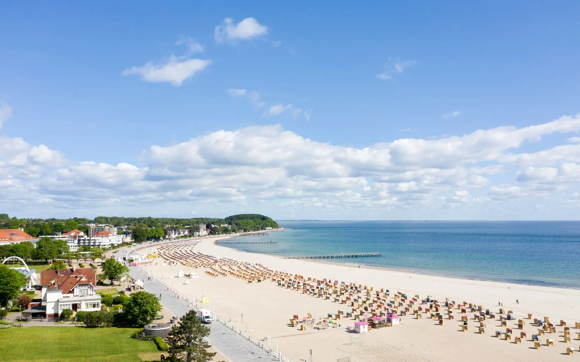 Strand mit vielen Stühlen und einem Gewässer im Hintergrund.