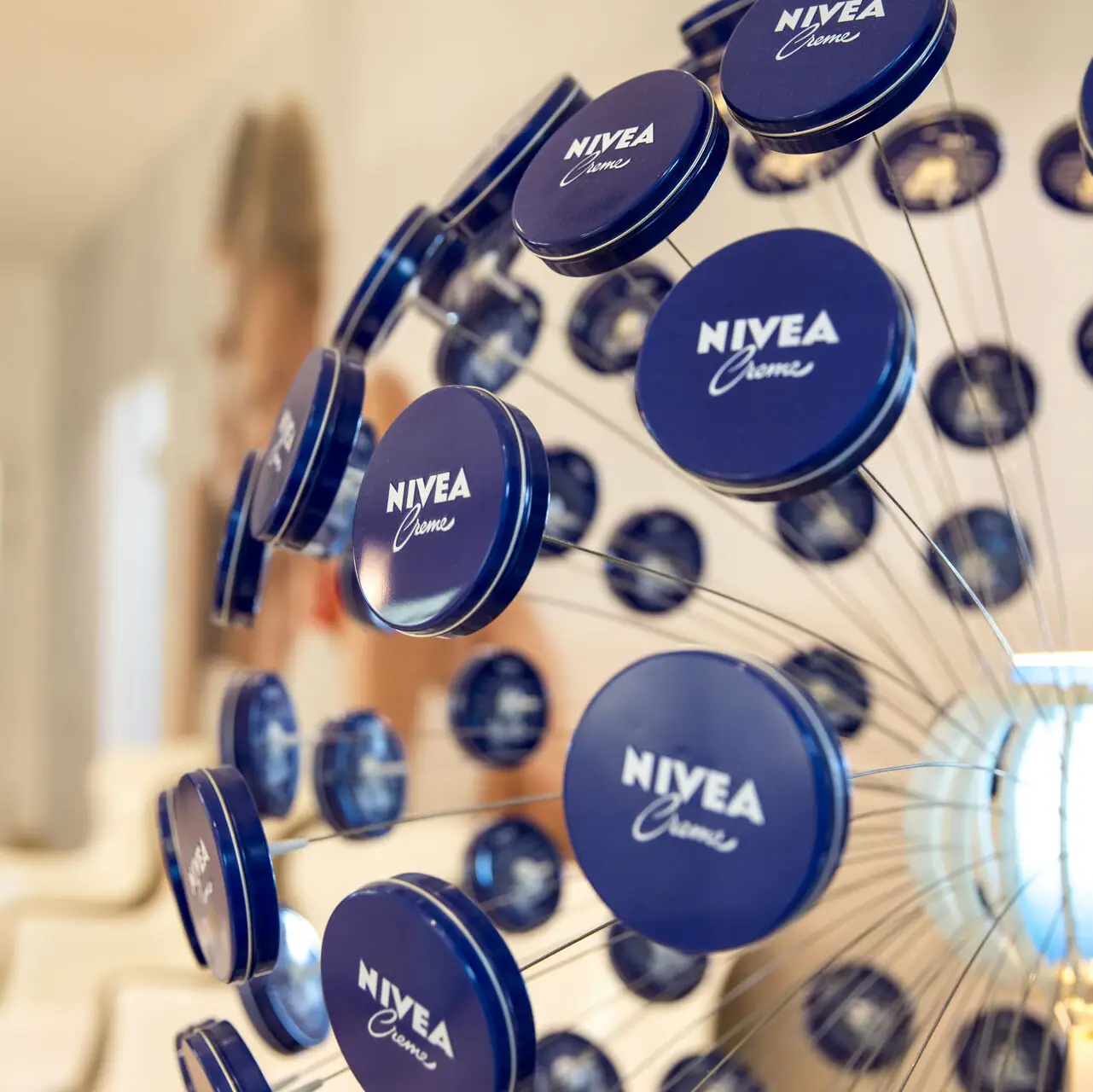 NIVEA Shop im aja Warnemünde Eine Gruppe blauer Dosen von NIVEA auf einem Draht.