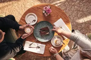 Café Eine Gruppe von Menschen sitzt an einem Tisch mit Kaffee und Kuchen.