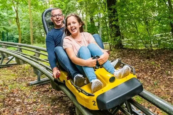 Ein Mann und eine Frau auf einer Achterbahn, beide lächeln.