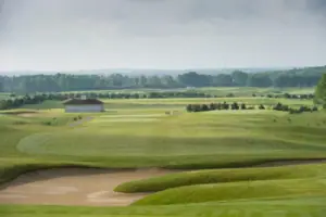 Golfplatz mit einem Gebäude und Bäumen im Hintergrund.