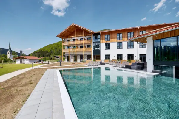 Schwimmbad vor einem Gebäude mit klarem Himmel im Hintergrund.