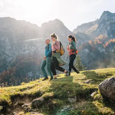 Aktivitäten & Erlebnisse Eine Gruppe von Menschen wandert auf einem Hügel mit Bergen im Hintergrund.