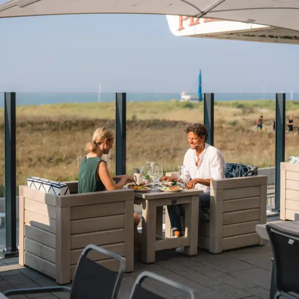 Terrasse im aja Warnemünde Ein Paar sitzt an einem Tisch im Freien.