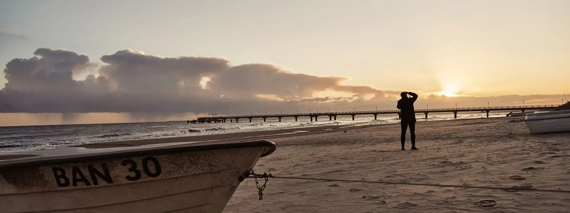 Strand von Bansin Eine Person steht am Strand mit einem Boot am Ufer.