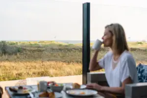 Terrasee Eine Frau sitzt an einem Tisch mit einer Tasse Kaffee.