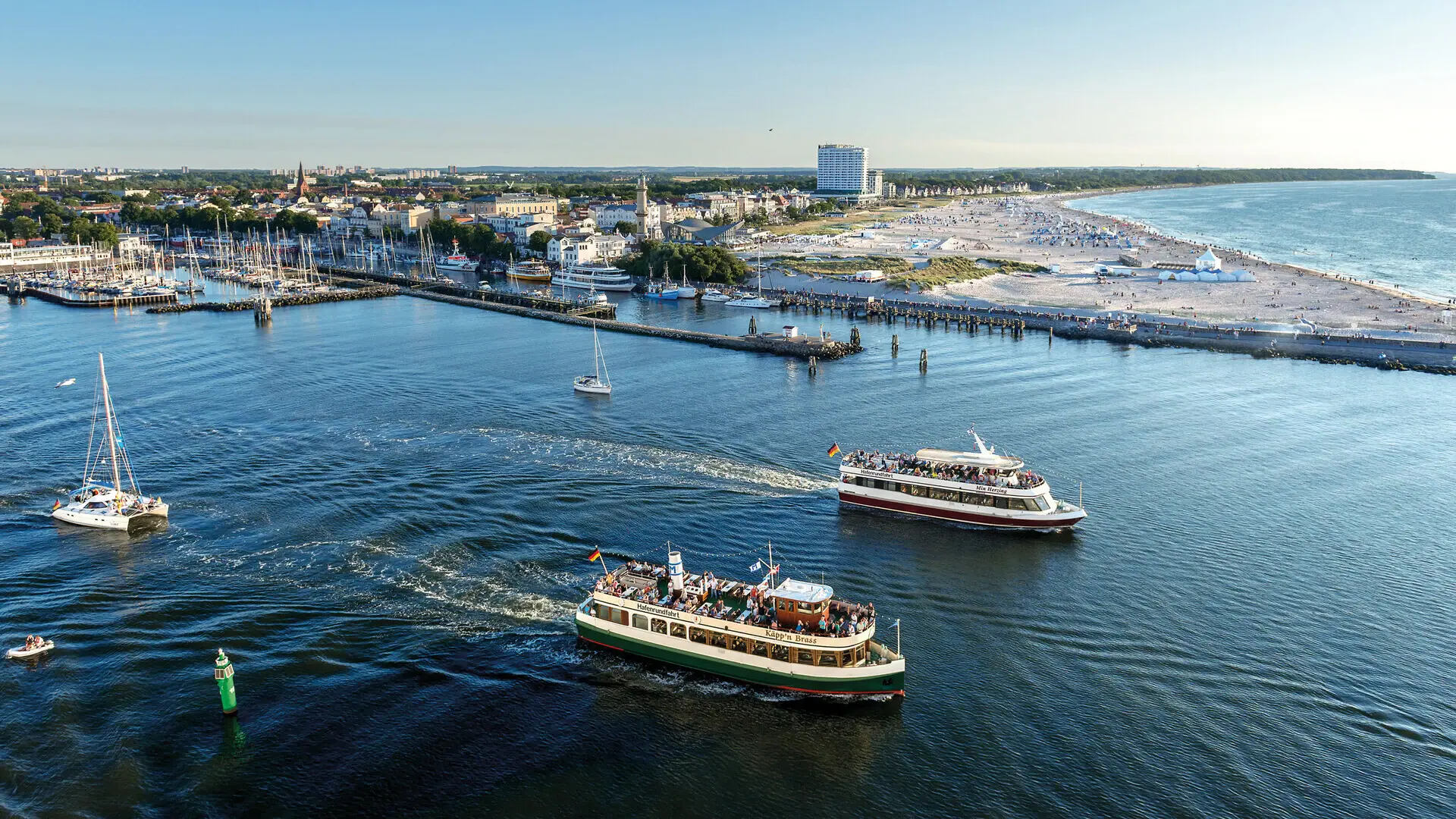 Viele Boote laufen aus dem hafen von Warnemünde bei blauem Himmel.