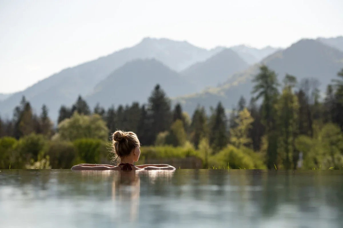 Eine Frau in einem Pool im aja Hotel Ruhpolding mit Bergen im Hintergrund.