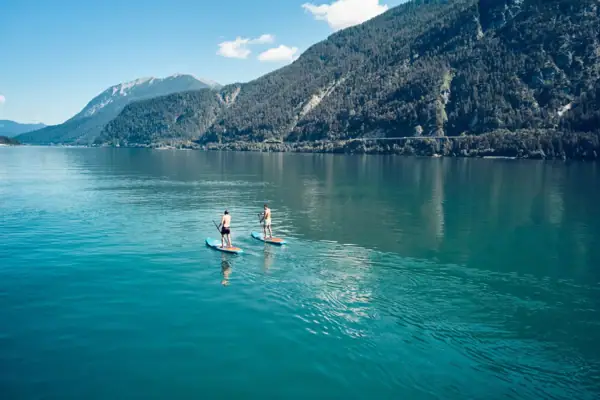 Zwei Personen auf Paddleboards auf einem See.