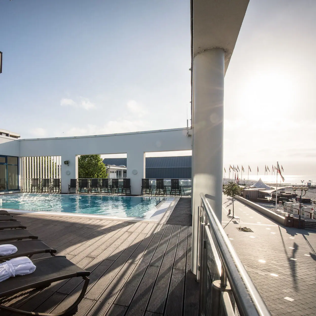 Schwimmbecken mit Liegestühlen und Holzterrasse im Freien.