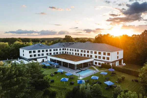aja Hotel Bad Saarow Ein Gebäude mit einem Pool und Sonnenschirmen.