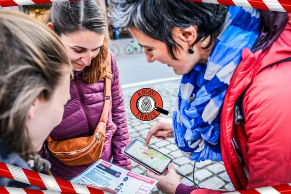 Krimi Trail Eine Gruppe von Frauen schaut auf ein Handy.