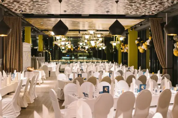 Das Restaurant im aja Bad Saarow festlich geschmückt. Verschiedene Tische mit weißen Tischdecken und Stuhlhussen. 