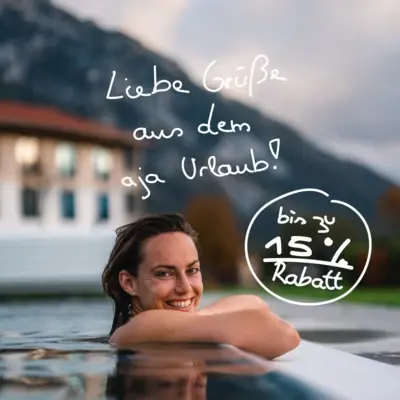 aja Frühlingswochen Eine lächelnde Frau im Pool mit einem Gebäude im Hintergrund.