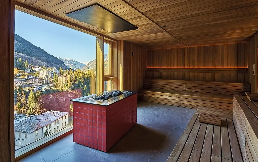 Eine Sauna mit großem Fenster und Ausblick auf die Berge.