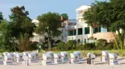 There are many white beach chairs on a beach and the aja Bansin can be seen in the background.