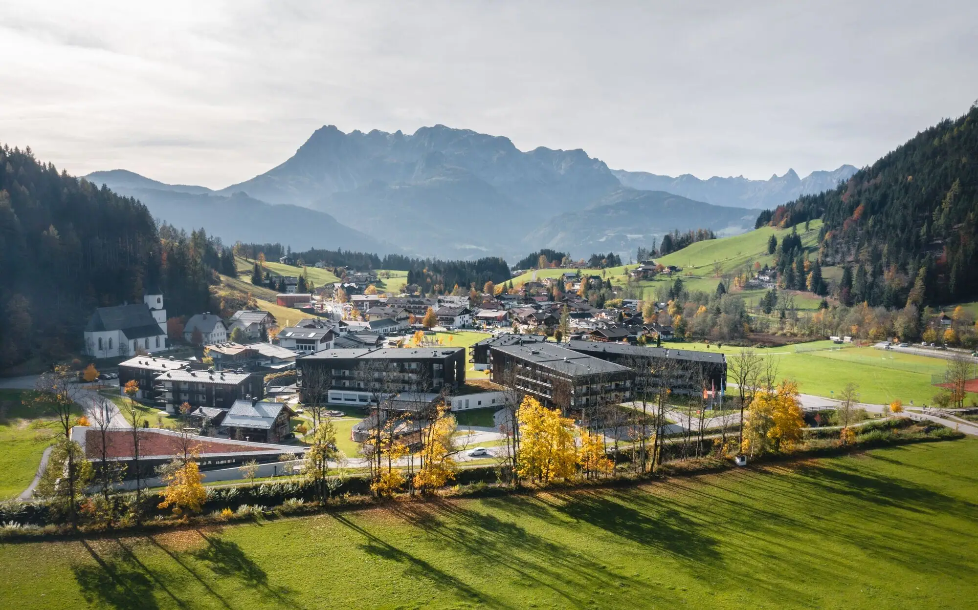 Ein Dorf mit vielen Gebäuden, umgeben von Gras und Bergen.