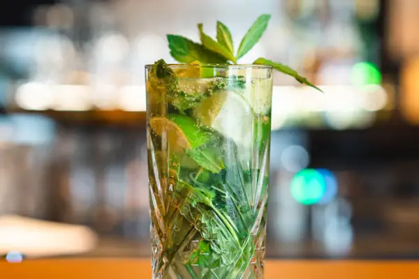 Ein Glas mit einem Cocktail aus Limetten und Minzblättern aus der aja Bar Ruhpolding.