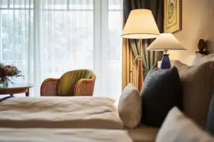 Doppelzimmer Ein Bett mit Kissen und einer Lampe neben einem Fenster.