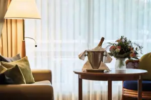 Senior-Suite Ein Tisch mit einem Eimer Champagner und Blumen darauf.