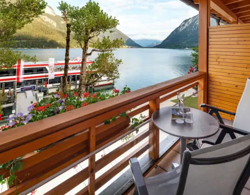 Balkon mit Blick auf den Achensee Ein Balkon mit einem Tisch und Stühlen mit Blick auf einen See.
