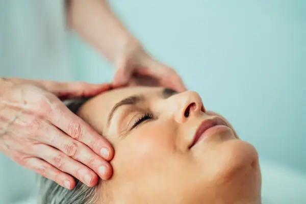 Eine Person massiert den Kopf einer Frau.