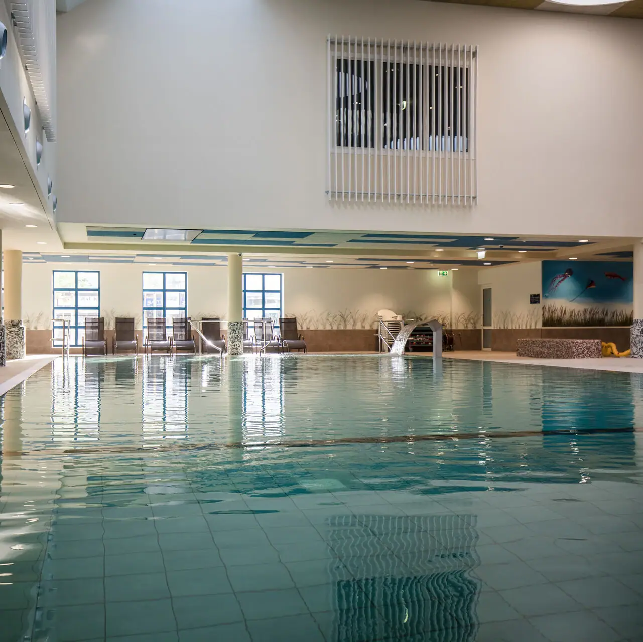 Großes Hallenbad mit klarem Wasser.