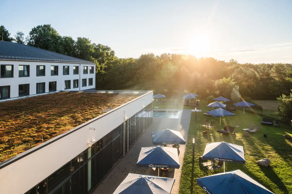 aja Bad Saarow Ein Gebäude mit Sonnenschirmen und Stühlen auf einer Wiese.