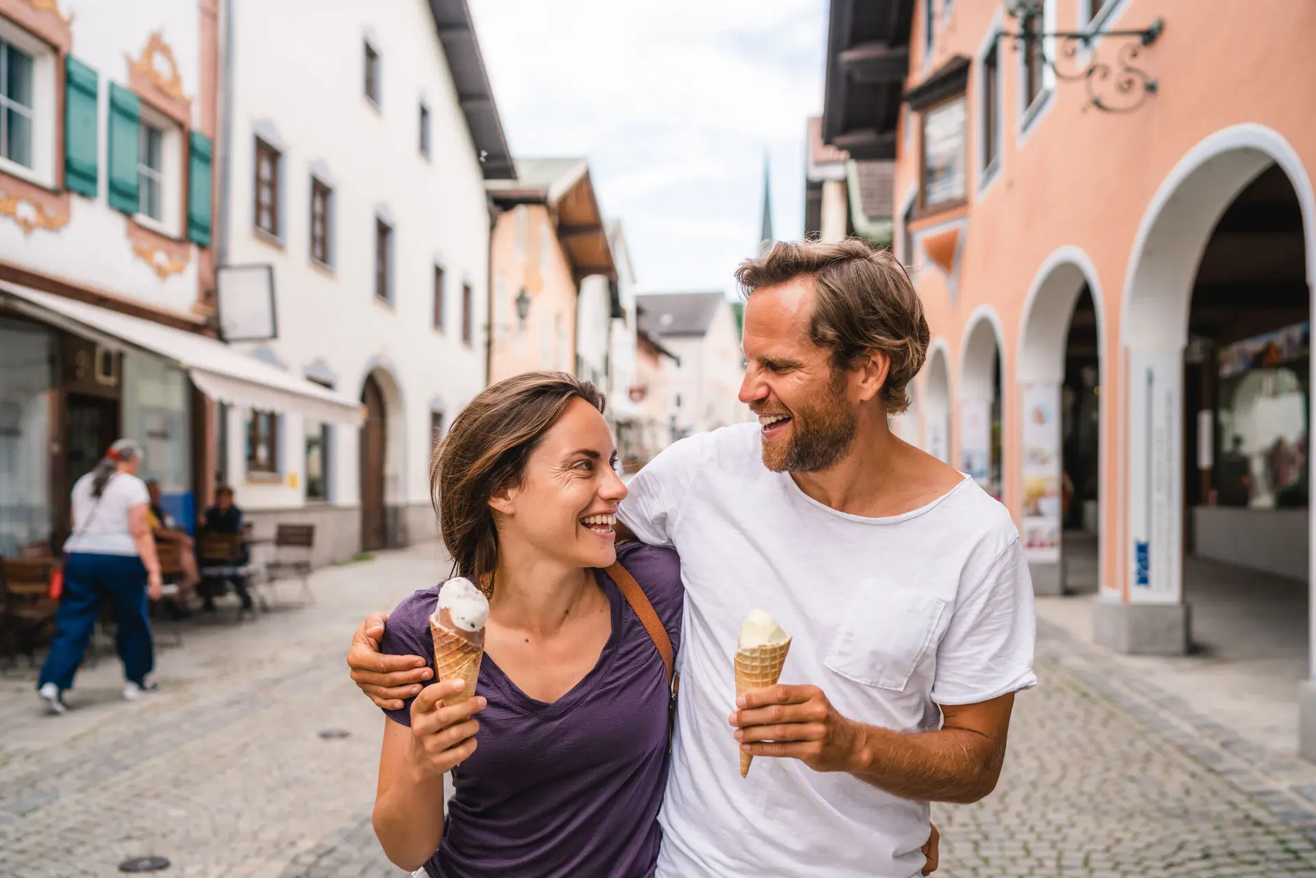 Ein Mann und eine Frau halten Eiswaffeln während sie durch Garmisch-Partenkirchen laufen.