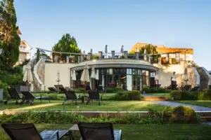 Nordperd & Villen Rasen mit Stühlen und Sonnenschirmen vor einem Gebäude